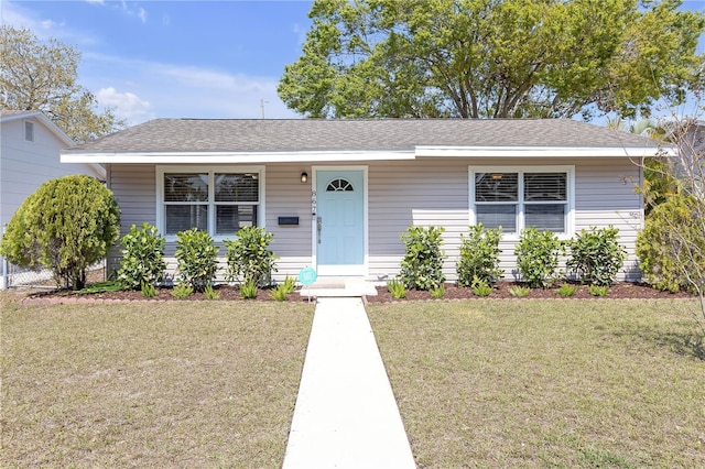 view of front facade with a front lawn and a shingled roof