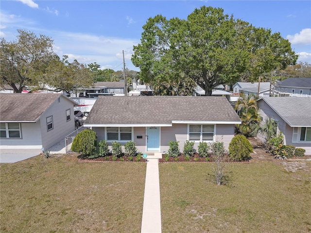 ranch-style house with a residential view, a front lawn, and roof with shingles