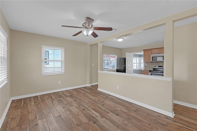 interior space with ceiling fan, baseboards, a healthy amount of sunlight, and wood finished floors