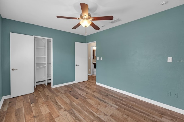 unfurnished bedroom featuring visible vents, ceiling fan, baseboards, wood finished floors, and a closet