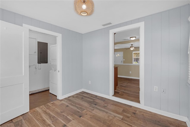 unfurnished room featuring visible vents, baseboards, electric panel, washer / dryer, and wood finished floors