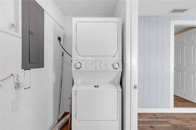 washroom featuring visible vents, stacked washer and dryer, electric panel, wood finished floors, and laundry area