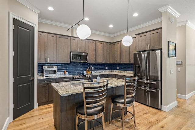 kitchen featuring light wood-style floors, dark brown cabinetry, appliances with stainless steel finishes, and ornamental molding