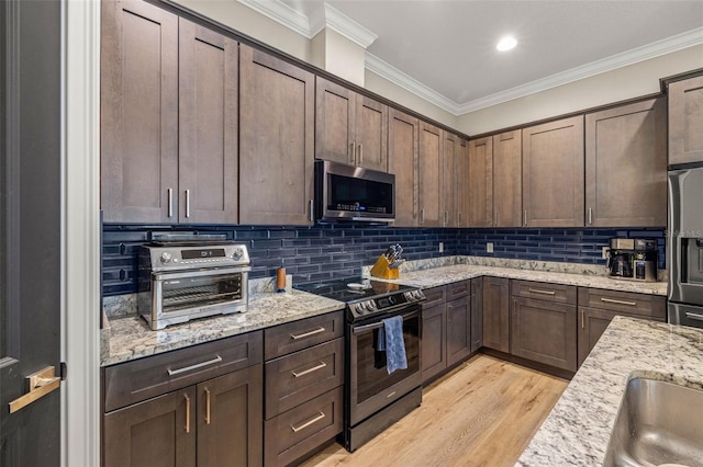 kitchen with dark brown cabinetry, backsplash, stainless steel appliances, and ornamental molding