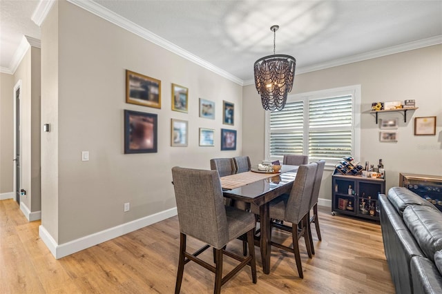 dining room with a chandelier, baseboards, crown molding, and light wood-style floors