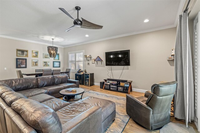 living room featuring light wood finished floors, baseboards, ceiling fan, and ornamental molding