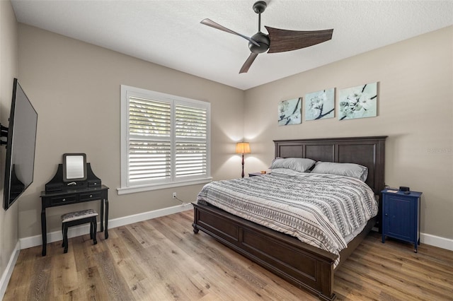 bedroom with light wood-type flooring, baseboards, and a ceiling fan