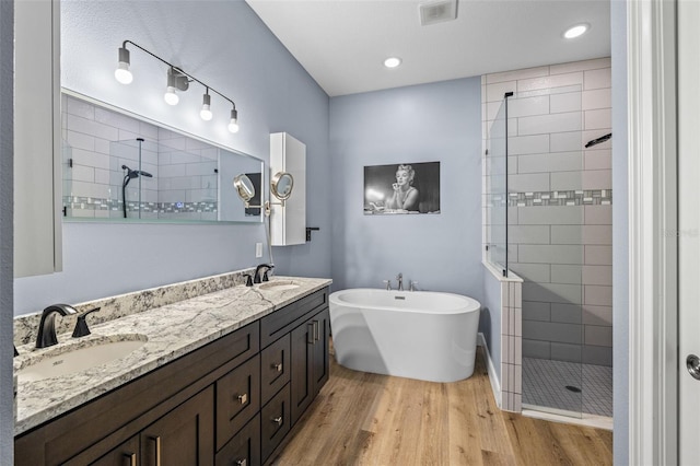 bathroom with wood finished floors, visible vents, a stall shower, and a sink