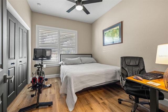 bedroom with a closet, ceiling fan, baseboards, and wood finished floors