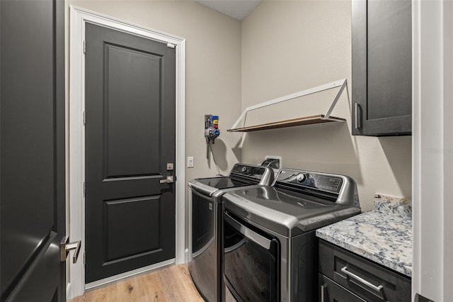 laundry area featuring washing machine and clothes dryer, cabinet space, and light wood-type flooring