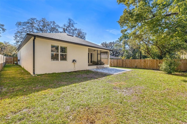 rear view of property with roof with shingles, stucco siding, a yard, a fenced backyard, and a patio area