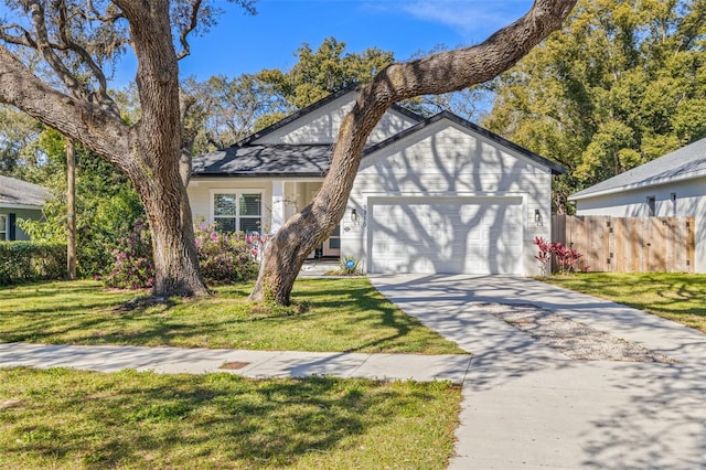 tudor home with an attached garage, concrete driveway, a front lawn, and fence