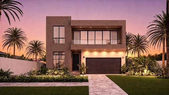 view of front facade featuring stucco siding, decorative driveway, a balcony, and a garage