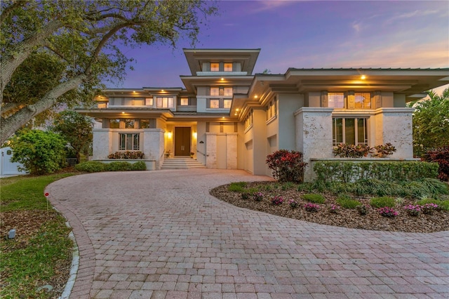 prairie-style house with stucco siding and decorative driveway