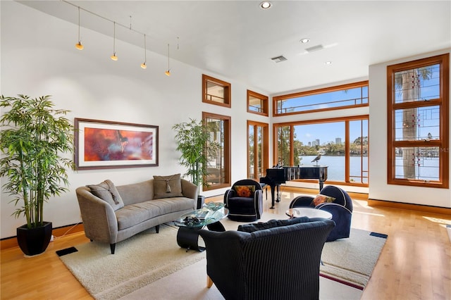 living area featuring visible vents, a water view, and wood finished floors