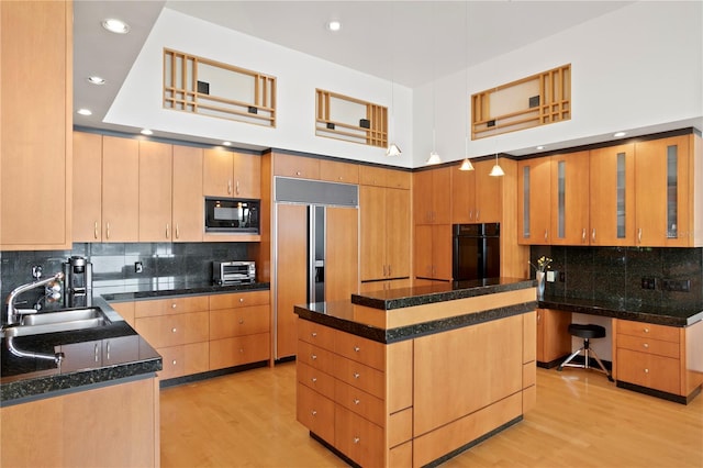 kitchen with a sink, backsplash, built in appliances, and light wood-style floors