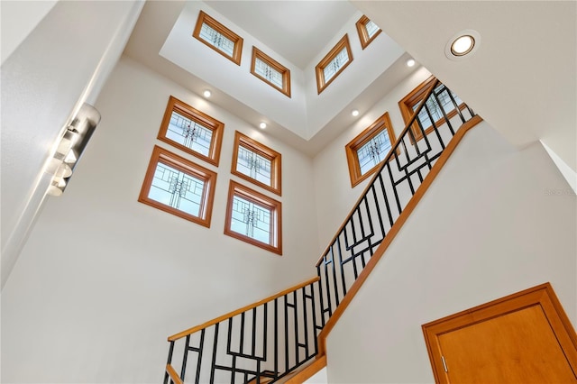 stairway featuring a wealth of natural light, a high ceiling, and recessed lighting