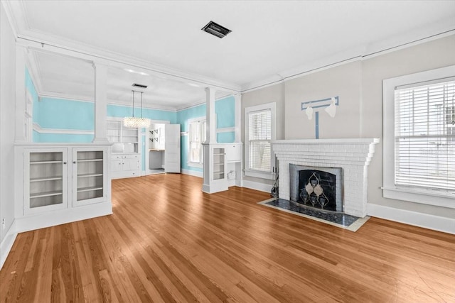 unfurnished living room with visible vents, a brick fireplace, built in shelves, ornamental molding, and wood finished floors