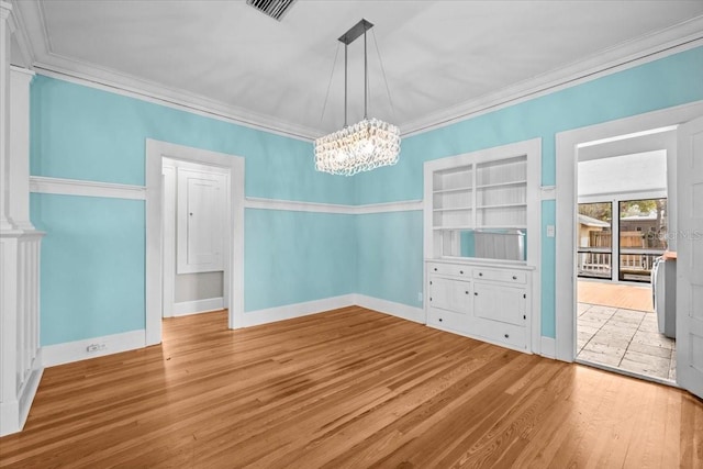 unfurnished dining area featuring visible vents, baseboards, wood finished floors, and crown molding