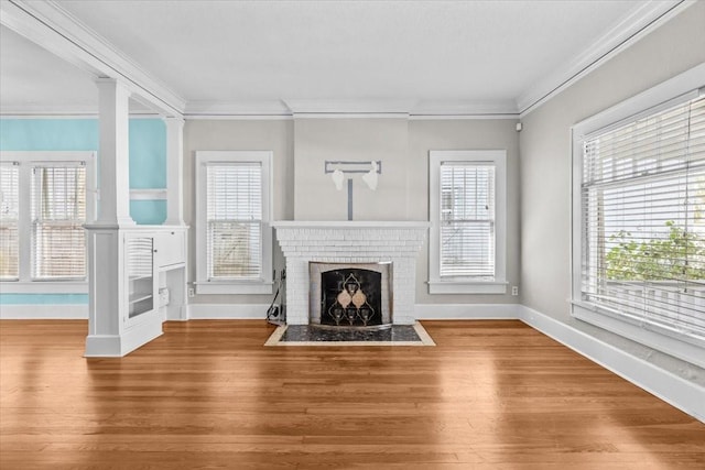 unfurnished living room with plenty of natural light, a fireplace, ornate columns, and wood finished floors