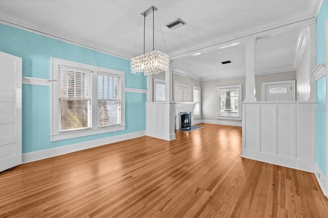 unfurnished living room with visible vents, a brick fireplace, crown molding, baseboards, and wood finished floors