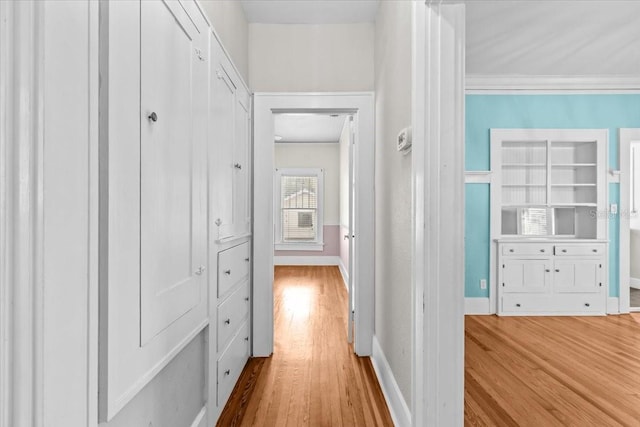 corridor featuring crown molding, built in features, wood finished floors, and baseboards