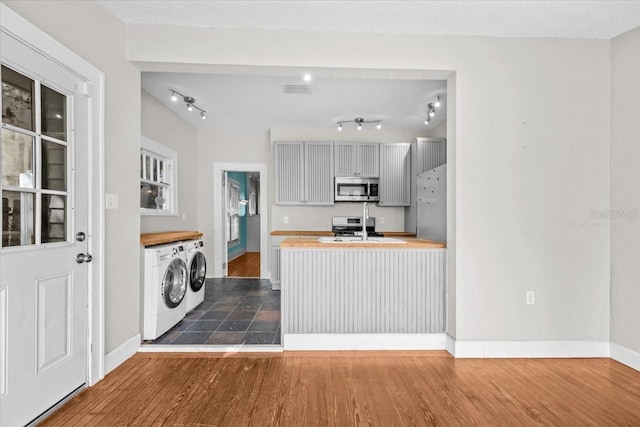 kitchen featuring visible vents, dark wood finished floors, separate washer and dryer, appliances with stainless steel finishes, and a sink