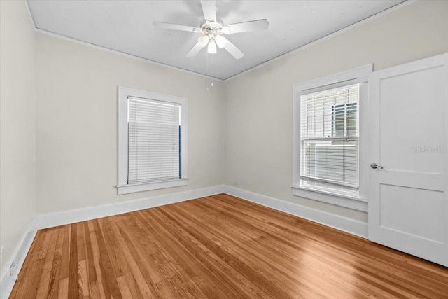 unfurnished room featuring ceiling fan, wood finished floors, baseboards, and ornamental molding