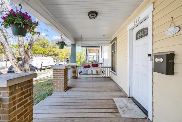 wooden deck featuring a porch and fence