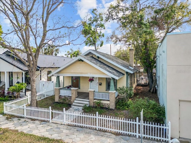 bungalow-style house featuring a gate, covered porch, a fenced front yard, and a chimney