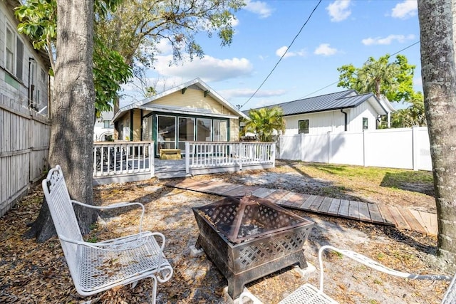 back of house with a wooden deck, an outdoor fire pit, and a fenced backyard