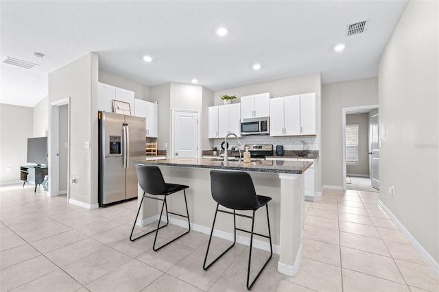 kitchen with stainless steel appliances, a kitchen breakfast bar, backsplash, and visible vents