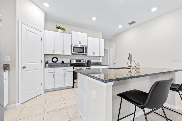 kitchen with a breakfast bar area, visible vents, a sink, stainless steel appliances, and tasteful backsplash