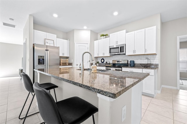 kitchen with tasteful backsplash, a kitchen breakfast bar, light tile patterned flooring, stainless steel appliances, and a sink