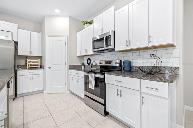 kitchen featuring dark stone counters, backsplash, appliances with stainless steel finishes, and white cabinetry