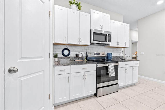 kitchen with dark stone countertops, backsplash, white cabinetry, stainless steel appliances, and light tile patterned floors