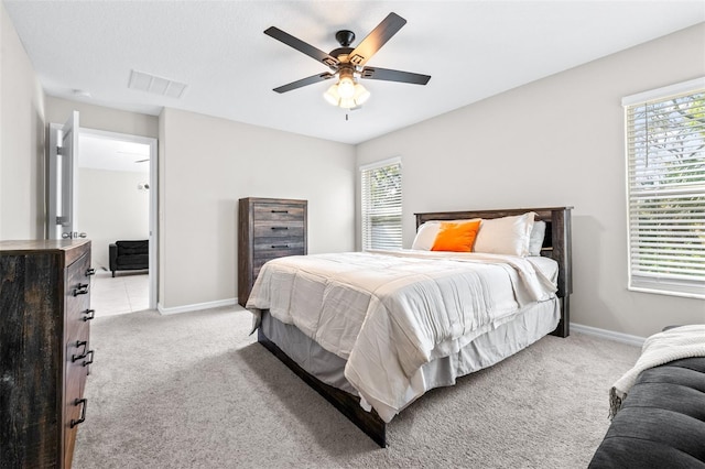 bedroom with multiple windows, baseboards, visible vents, and light carpet