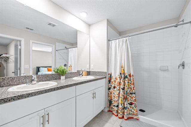 bathroom featuring tiled shower, visible vents, and a sink