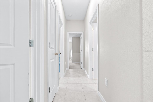 corridor with light tile patterned flooring and baseboards