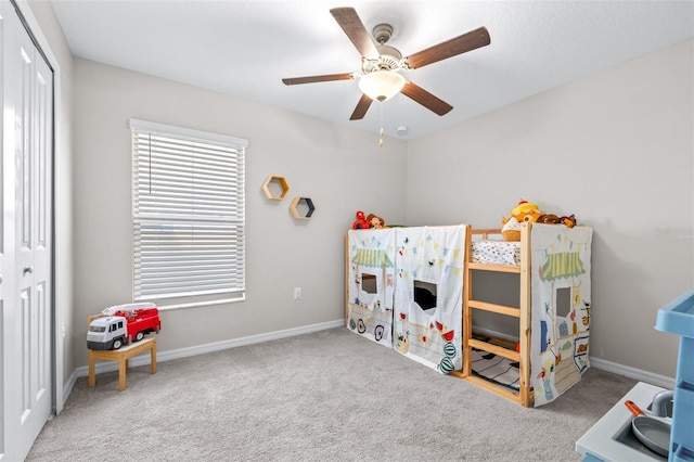 carpeted bedroom with a closet, baseboards, and ceiling fan