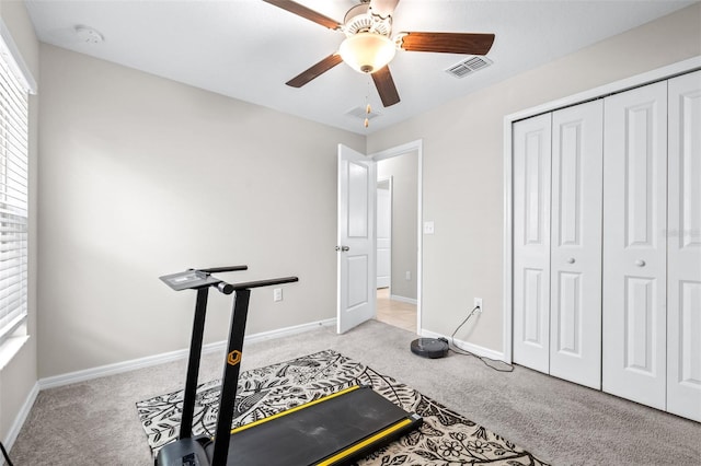 exercise area featuring visible vents, baseboards, light colored carpet, and a ceiling fan