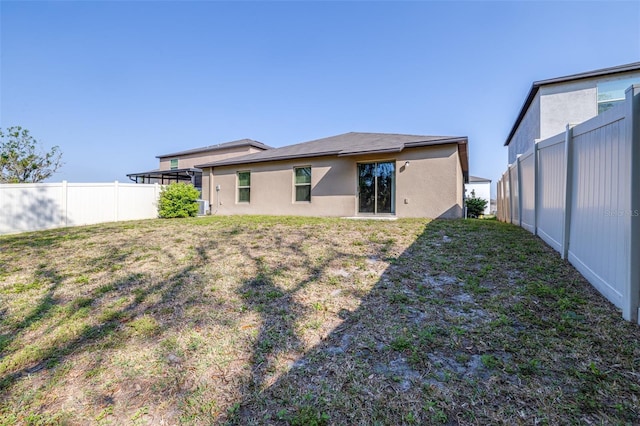 back of property with a yard, stucco siding, and fence