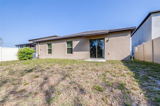 back of house with stucco siding, cooling unit, a yard, and fence