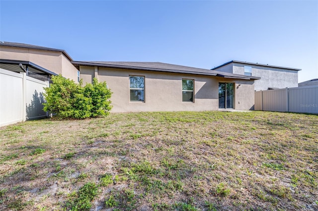 back of property with fence, a lawn, and stucco siding