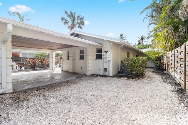 view of home's exterior with an attached carport, fence, and stucco siding