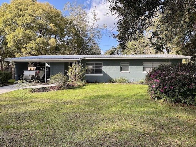 back of house featuring a yard, an attached carport, metal roof, and concrete driveway