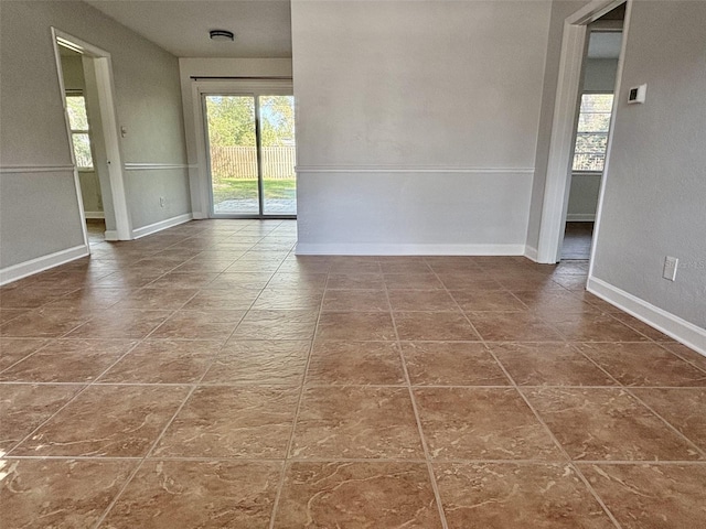 empty room featuring a wealth of natural light and baseboards