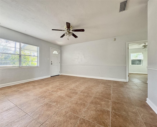 spare room with visible vents, a textured ceiling, baseboards, and ceiling fan