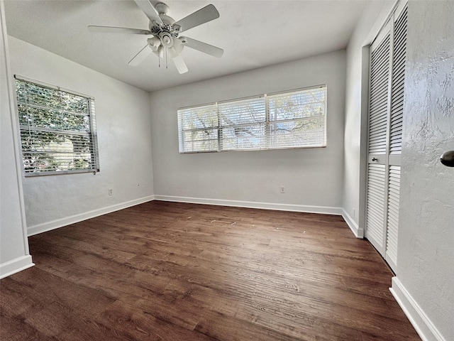 unfurnished bedroom featuring dark wood-type flooring, baseboards, a closet, and ceiling fan