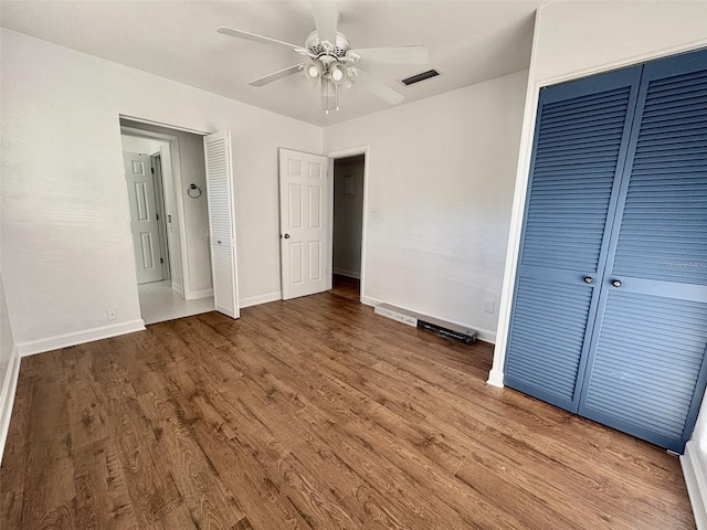 unfurnished bedroom featuring wood finished floors, visible vents, a closet, and baseboards